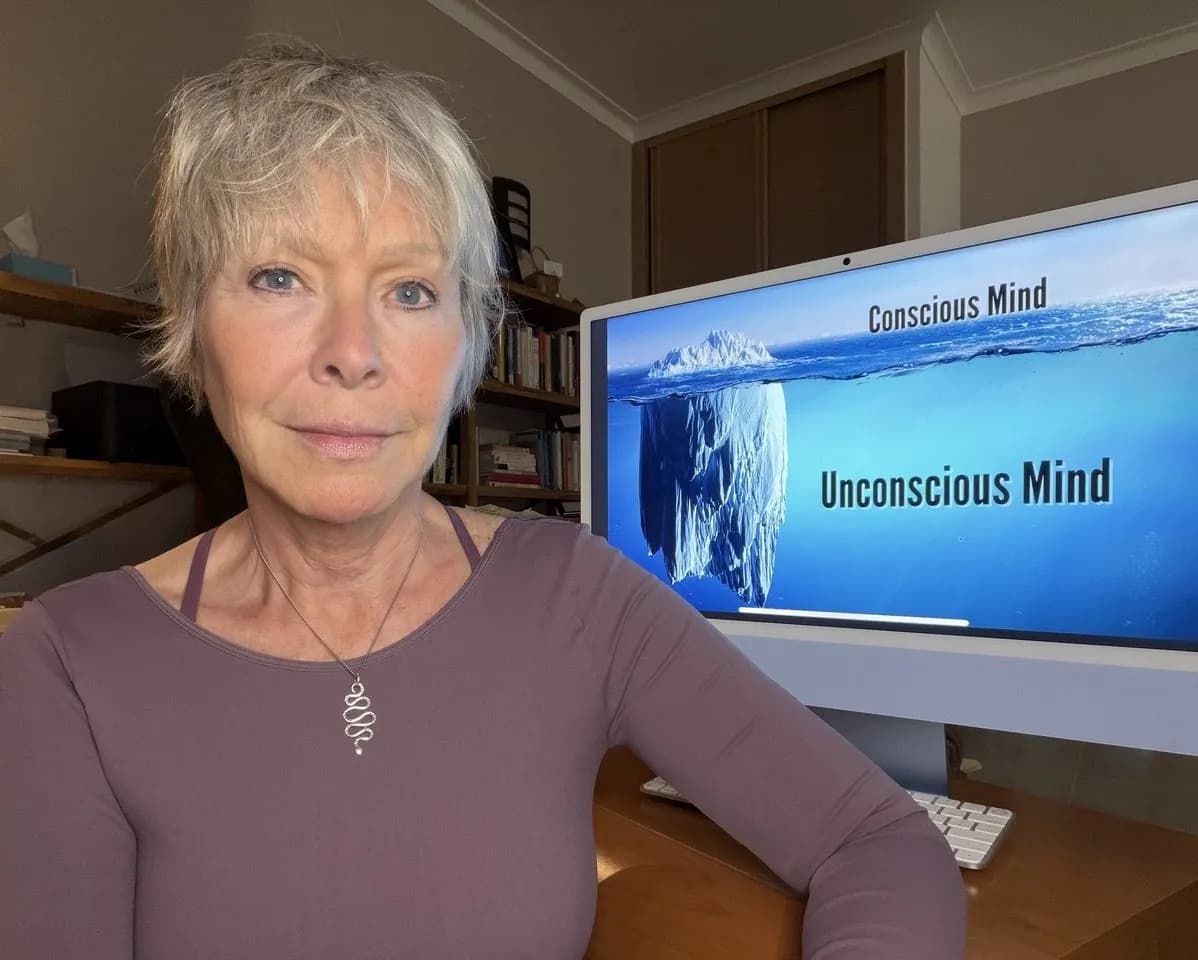 Becca Williams sitting in front of a computer monitor displaying an iceberg diagram representing healing with sacred plant medicine, labeled Conscious Mind and Unconscious Mind.